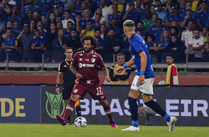 Um grupo de pessoas disputando uma partida de futebol Fluminense x Cruzeiro.