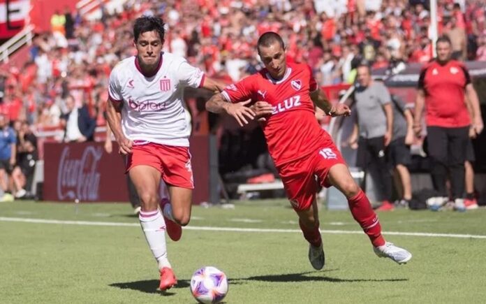 Dois jogadores de futebol correm pela bola em um campo de futebol durante a Copa Argentina 2023.